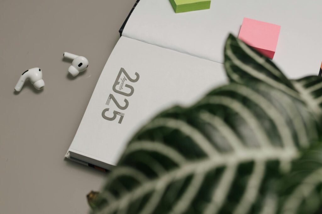 Open 2025 planner with AirPods and sticky notes, creating a modern workspace vibe.